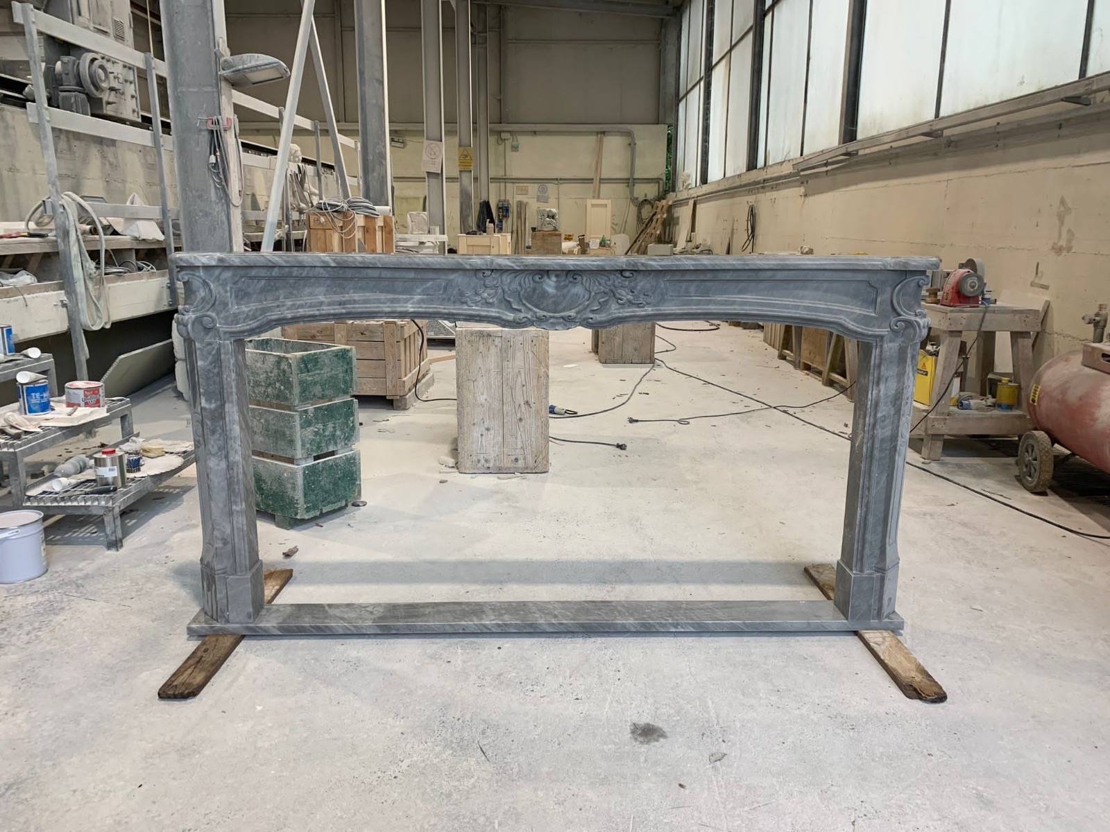 Front view of a Bardiglio Nuvolato marble Renaissance fireplace mantel with carved shell and scroll details, photographed in the workshop