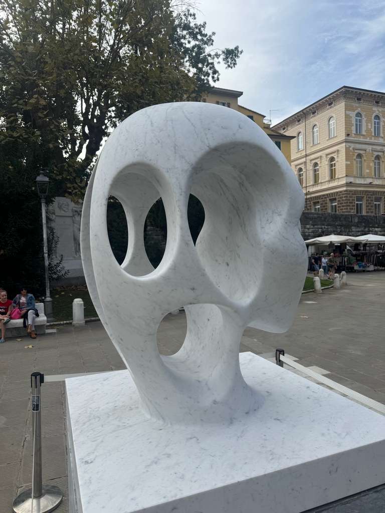 Carrara marble head sculpture with elongated profile and oval voids carved through the skull, on a marble plinth