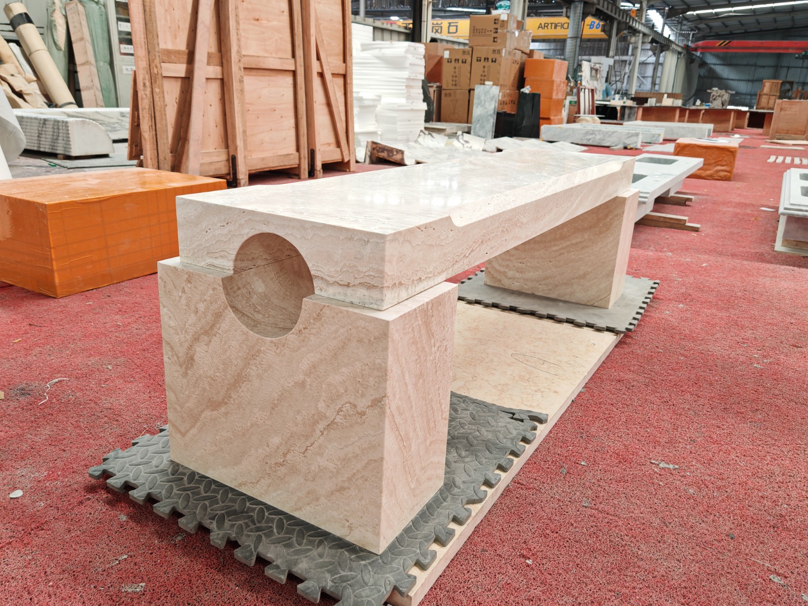 Travertine bench with circular cutout in the leg support, photographed in the workshop