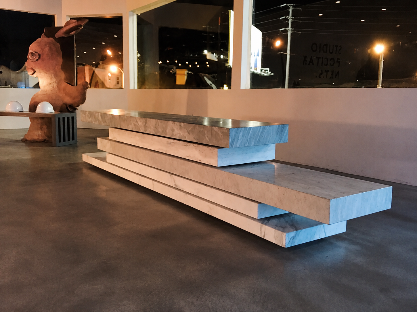 Sculptural bench of stacked 5 cm marble slabs in contrasting stones, assembled into layered seating