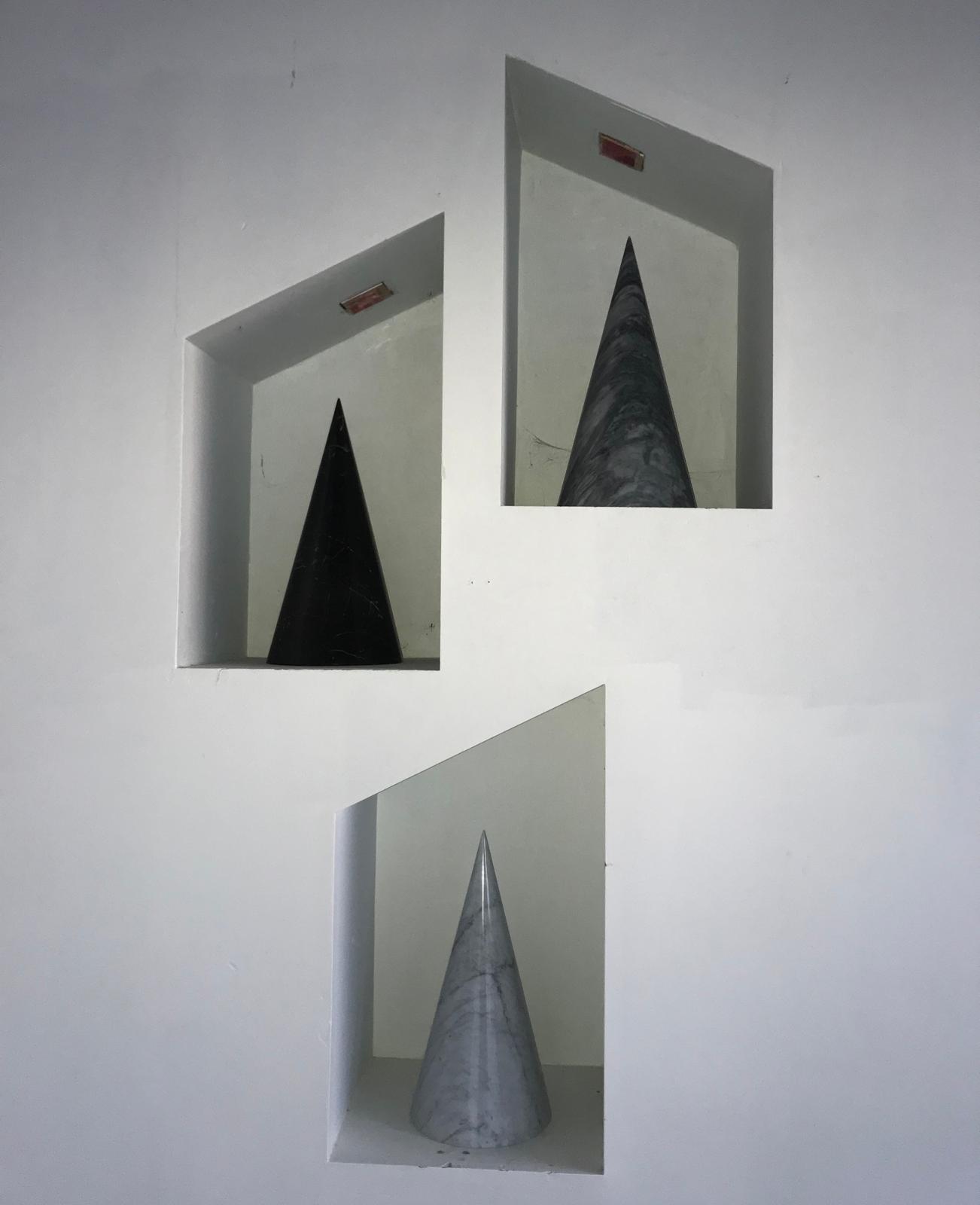 Three marble cones — black, grey-veined and white Carrara — set in asymmetric wall niches