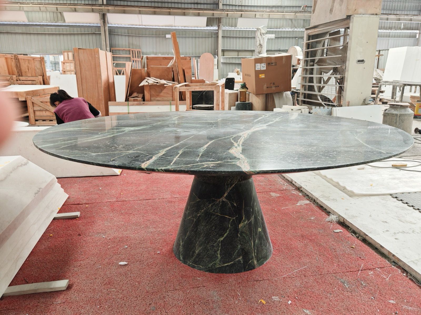 Round dark green marble table on a conical green marble pedestal in the workshop