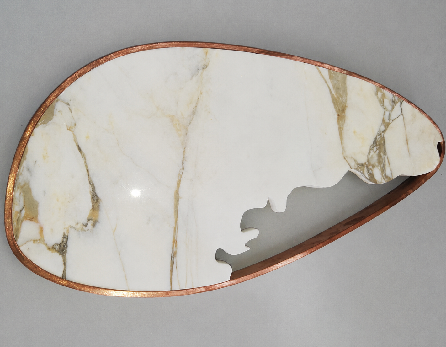 Sculptural teardrop sconce crafted from a single slab of Calacatta marble, with a naturally torn organic edge and delicate hand-formed copper frame