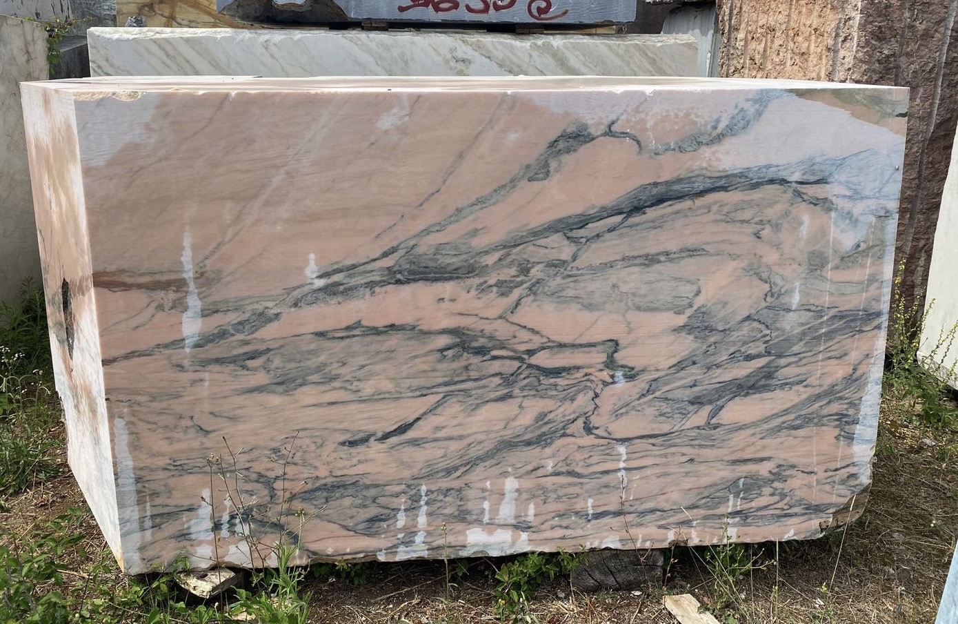 Rough raw block of Pink Portugal marble with dark grey and blue veining, freshly quarried