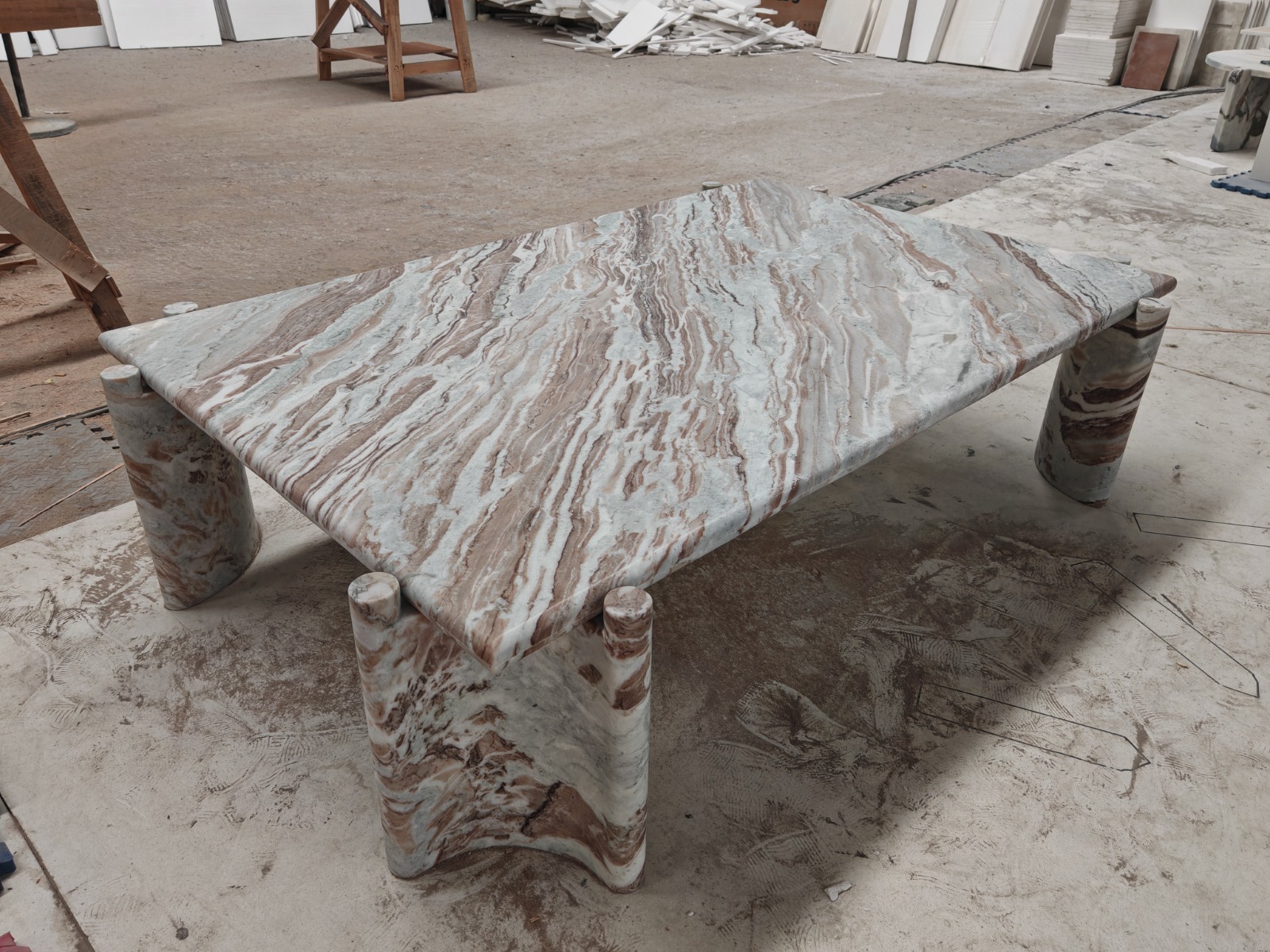 Low rectangular coffee table with a swirling grey, white, and rust marble top resting on three cylindrical marble legs
