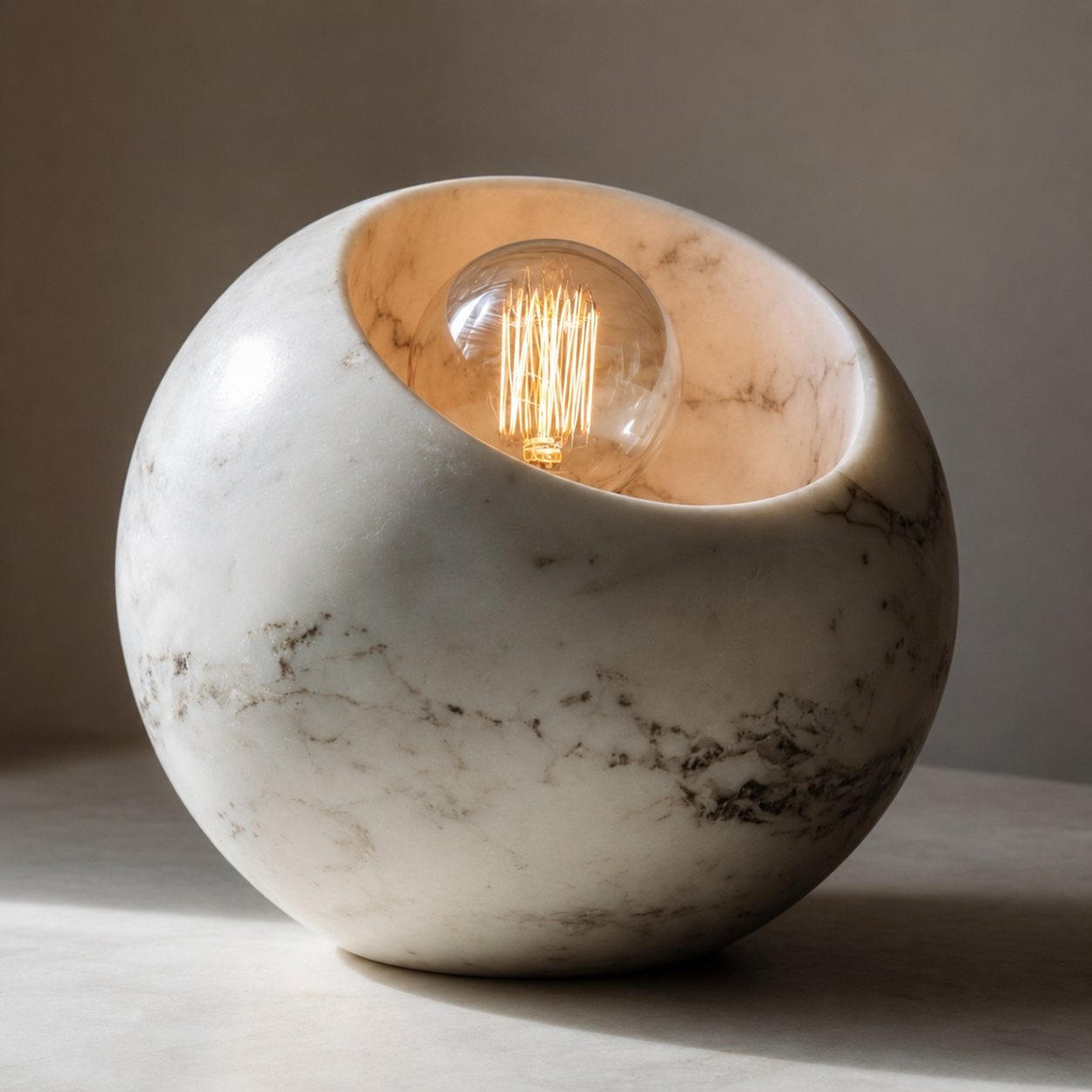 Round white marble lamp with a warm glowing bulb recessed into the top opening