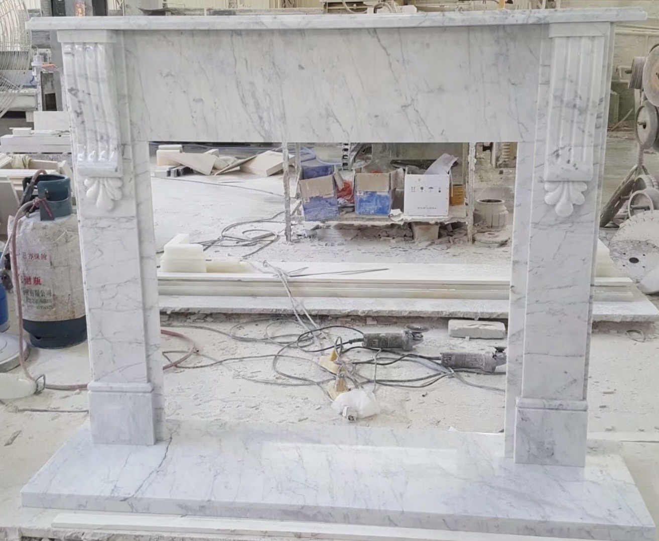 Classical Carrara Statuary Venatino marble fireplace mantel with fluted pilasters and carved corbels, photographed in the workshop
