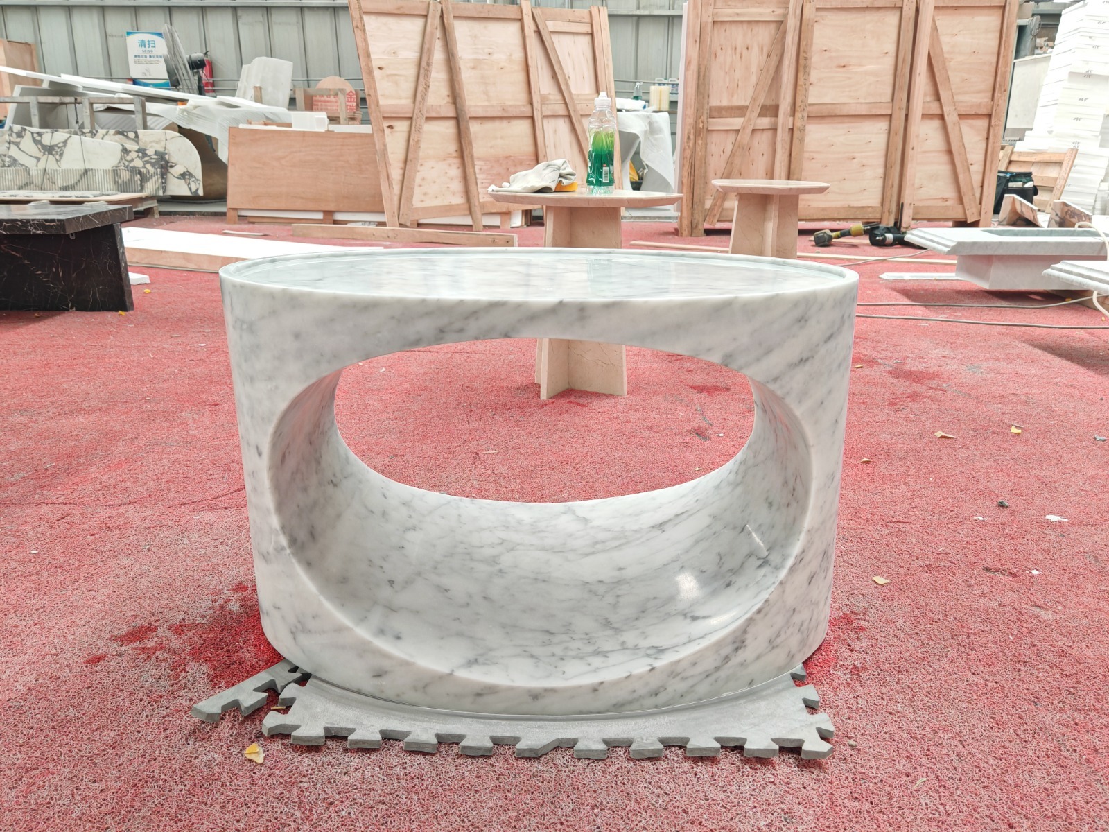 Oval Carrara marble coffee table carved as a single continuous loop, photographed head-on in the yard