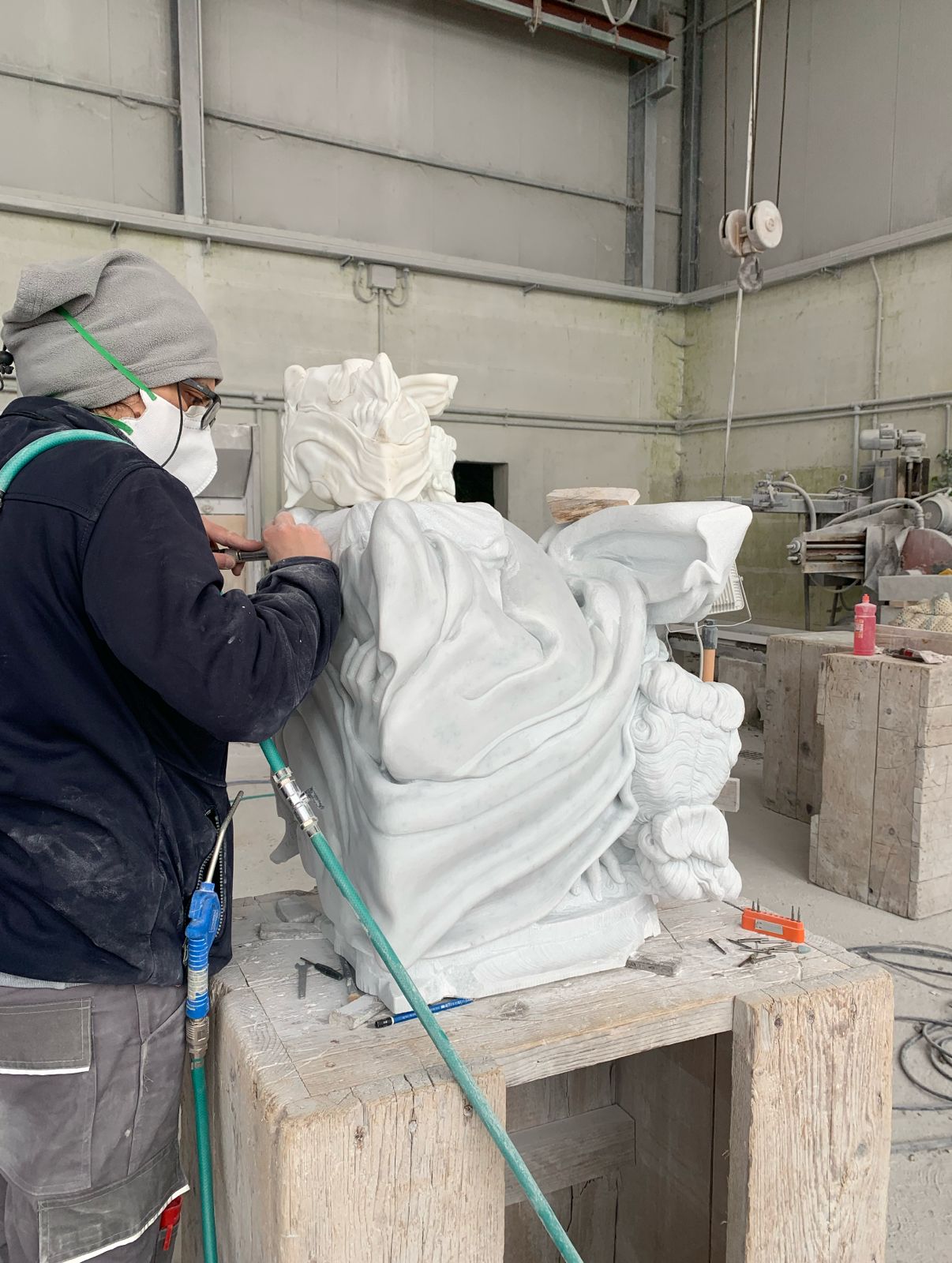 Sculptor finishing the back of a draped marble bust with flowing hair and fabric