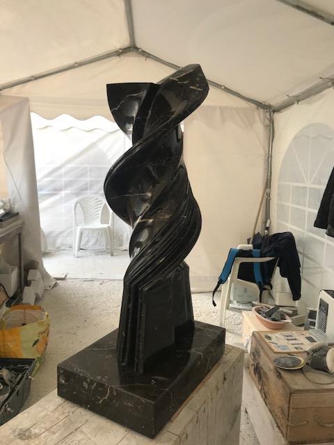 Tall spiral black marble sculpture in the workshop tent