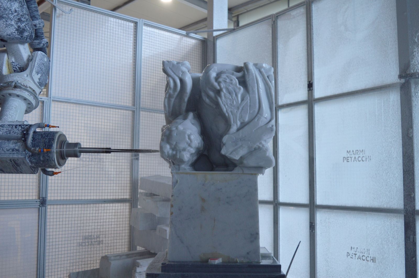 A gargoyle-like marble sculpture being carved by a robotic arm