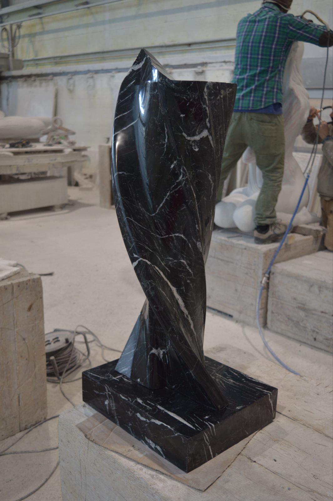 Black marble twisted sculpture with white veins in the workshop
